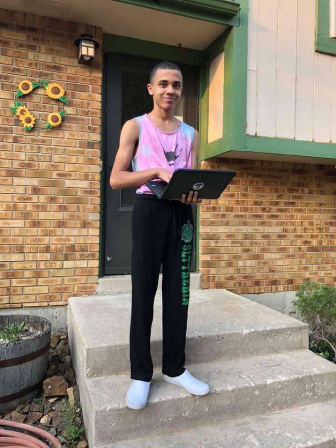 Cole Russell stands outside his house with his laptop for online school. 