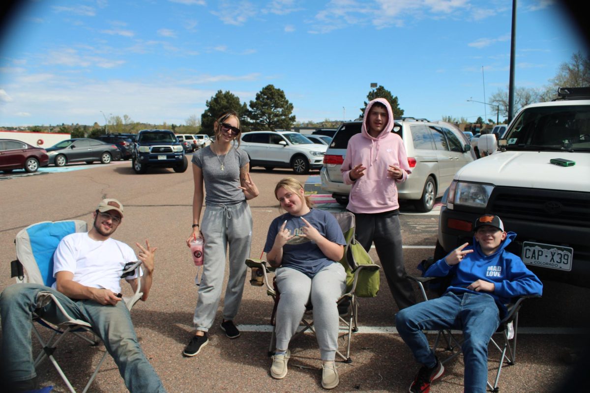 A group of seniors sitting around a campfire in the parking lot as part of a senior prank.