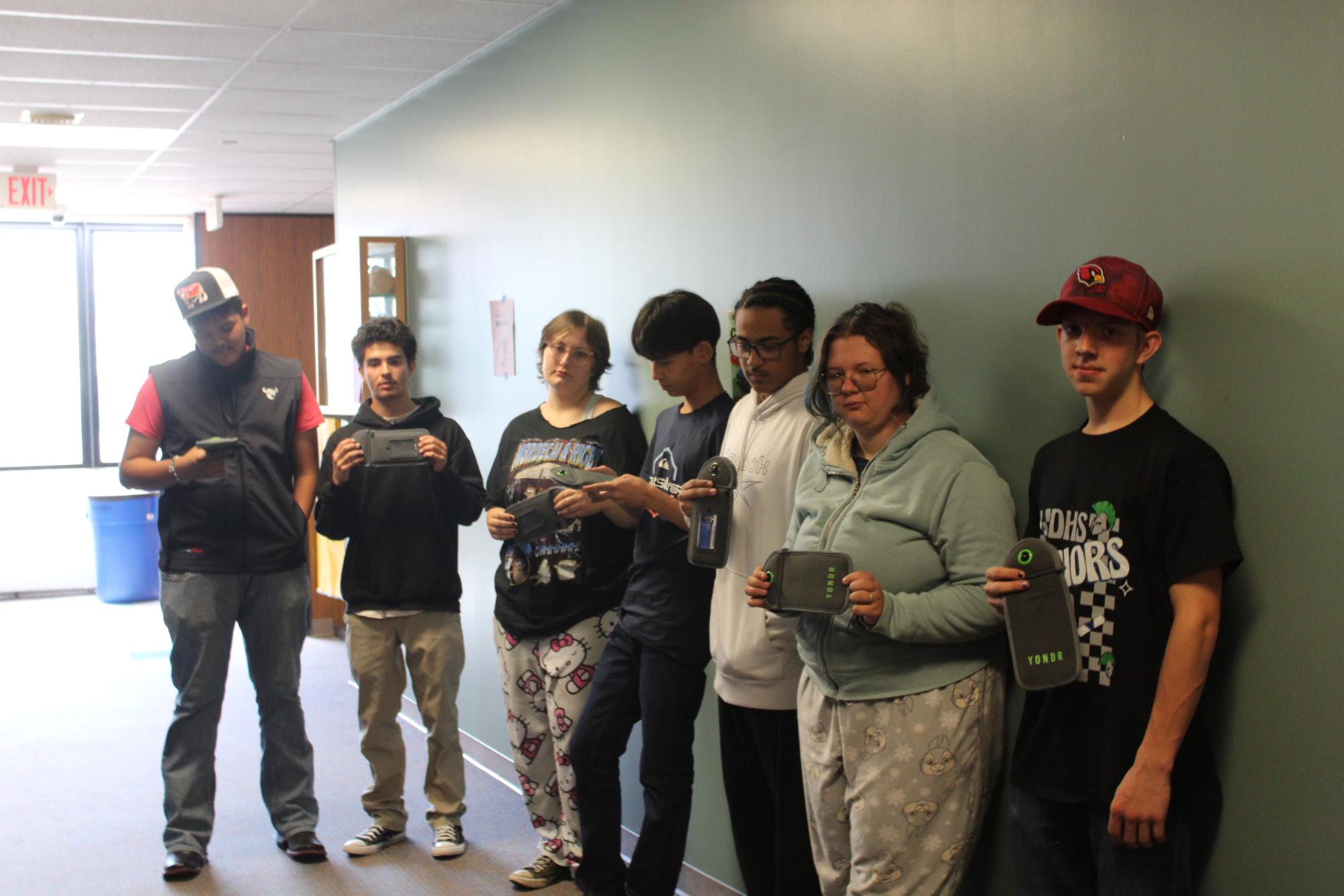 A group of Doherty students posing with their Yondr pouches in the science hallway at Doherty High School. 