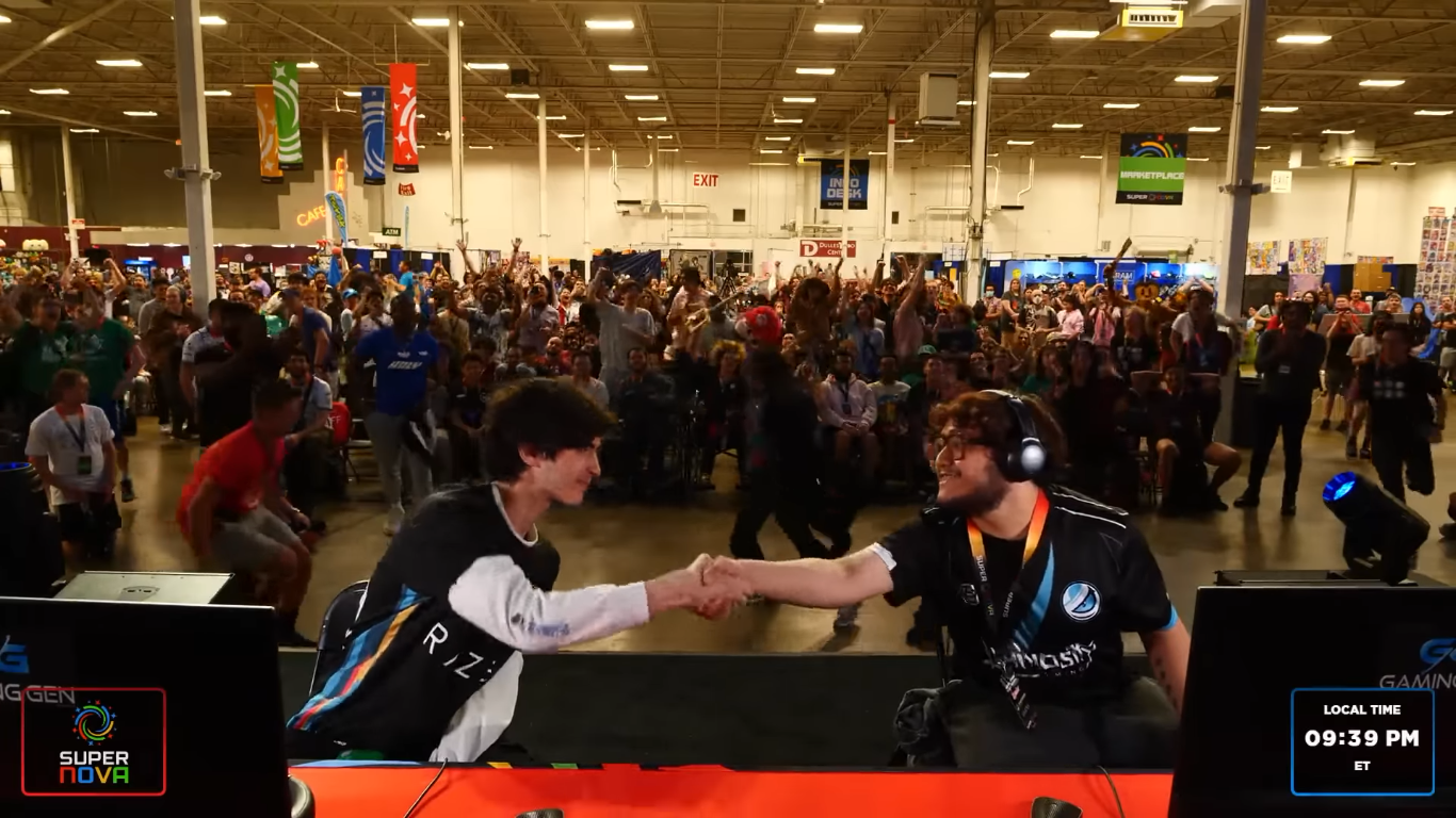 MKLeo (right) shaking the hand of Luugi (left) in front of a massive cheering crowd after a reverse 3-0.