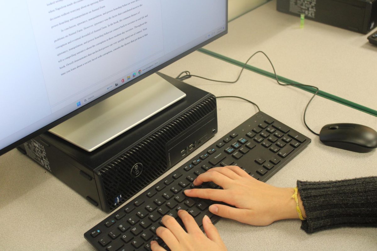 A student sits at a desktop finishing her Animal Farm essay. 