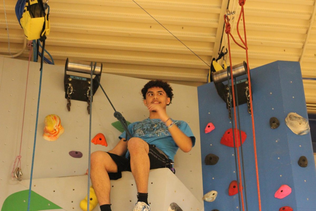 Student Brandon Jaquez at the top of Doherty rock wall.