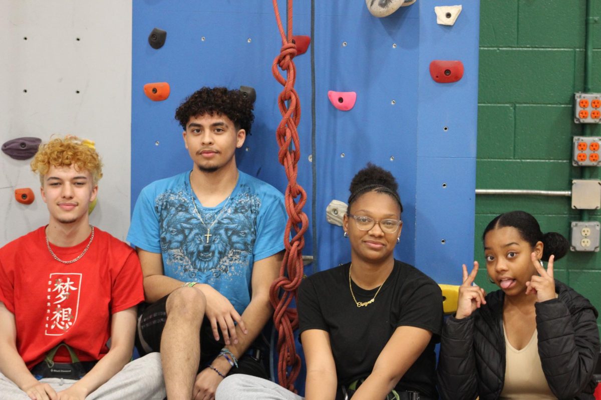 Friends Brandon Jaquez, Charizma McCall, Winter Reaves, and Vincent Garcia sitting at the base of Doherty's rock wall.